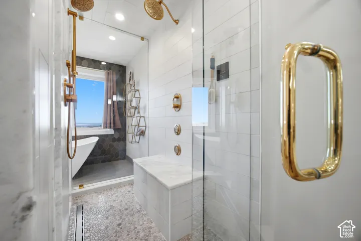 Glass-enclosed shower with pebble-finish flooring, a built-in bench, and dual shower heads