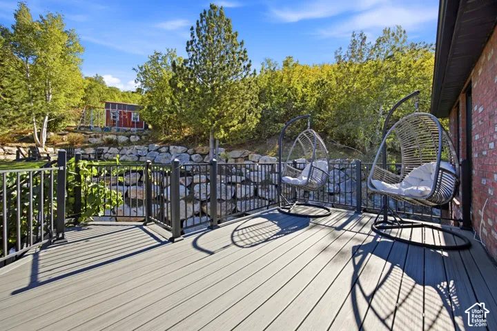 Expansive deck with wood-finish decking, black metal railing, and brick exterior