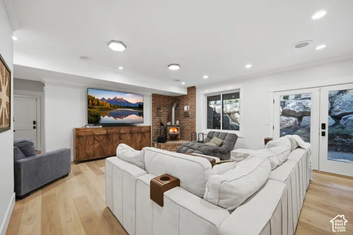Recessed lighting, wood-finish flooring, exposed brick accent wall, freestanding wood-burning stove, and French doors