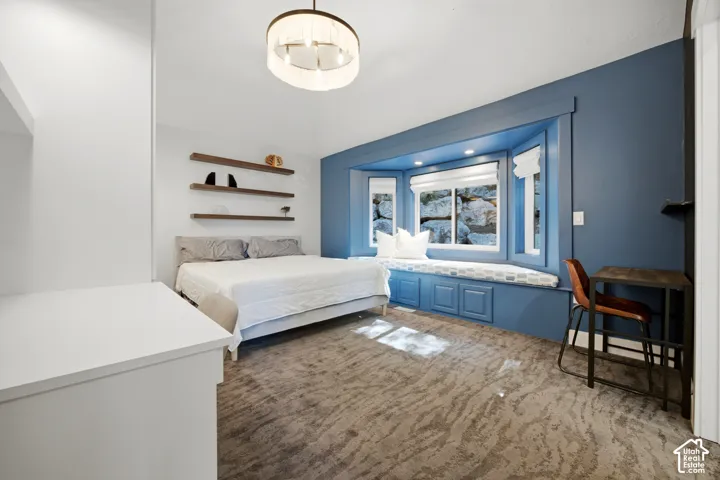 Carpeted interior space featuring a built-in window seat with integrated storage, wood-finish floating shelves, and a contemporary ceiling fixture