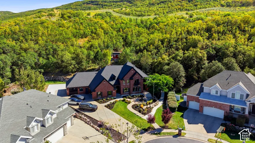 Red brick facade, black shingled roof, manicured landscaping, multi-level design, and concrete driveway