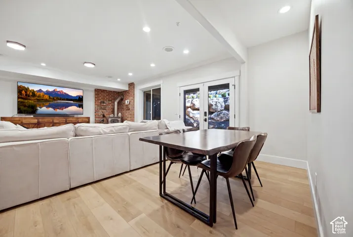 Recessed lighting, light wood-finish flooring, exposed brick wall, and a wood-burning stove