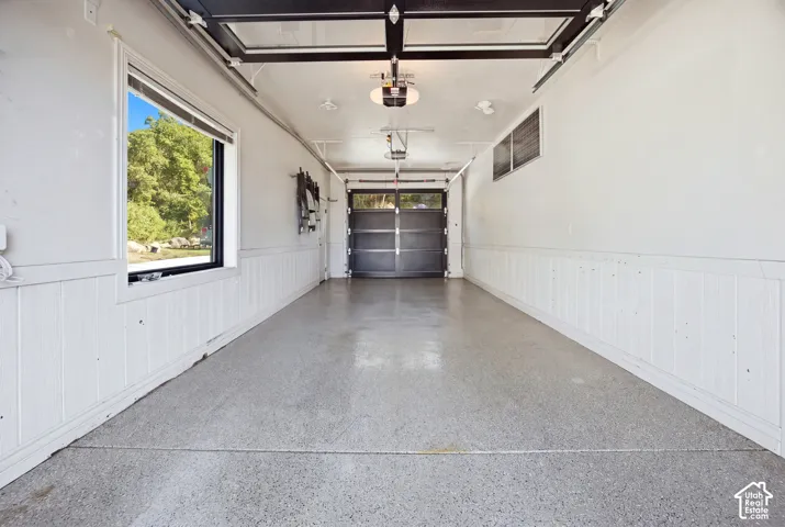 Garage with an epoxy floor finish, wainscoting, and a window