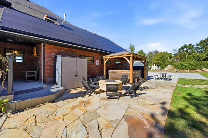 Stone patio with a fire pit, covered outdoor spa, and a concrete pad