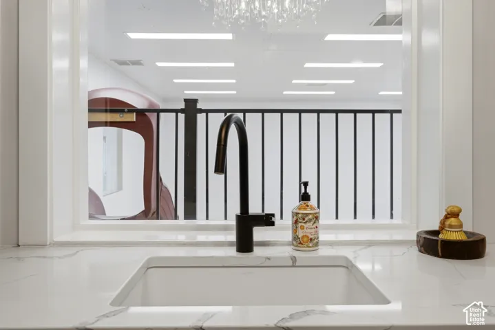 Undermount sink with a matte black faucet, set into a white countertop with gray veining