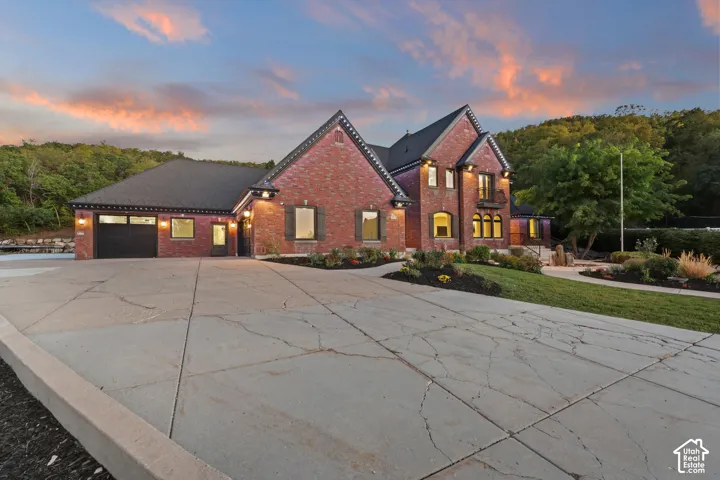 Brick exterior with dark shutters, attached two-car garage, arched entryways, and professional landscaping