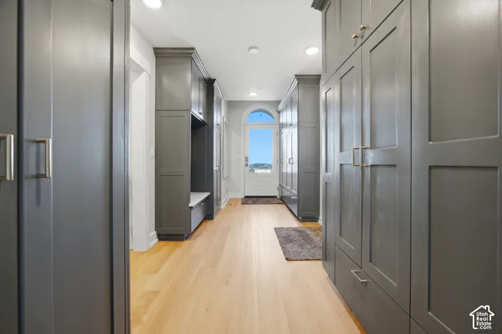 Hallway featuring built-in gray cabinetry, integrated bench seating, and light wood-finish flooring