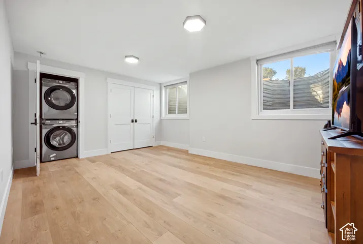 Light wood-finish flooring, recessed lighting, and a stacked washer and dryer unit