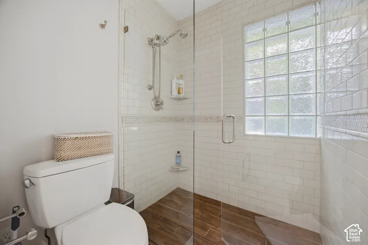 Glass-enclosed shower with subway tile walls, a decorative tile accent, and a glass block window