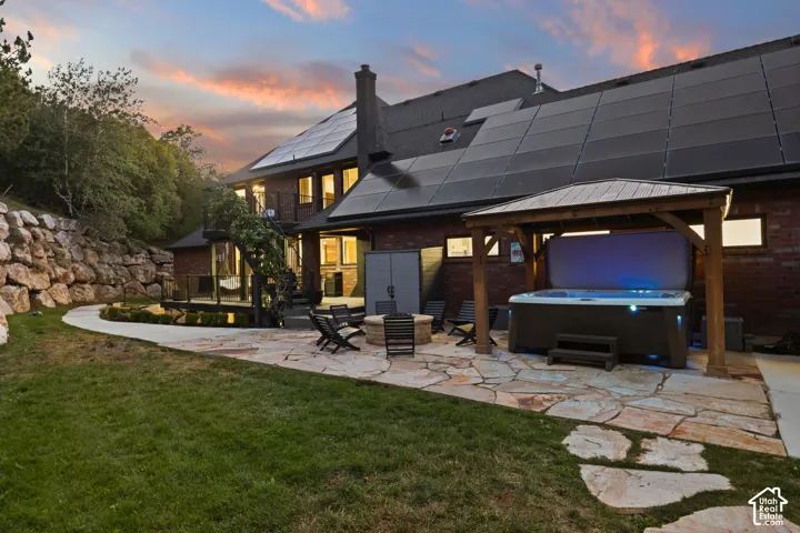 Expansive stone patio featuring a hot tub with a wooden gazebo