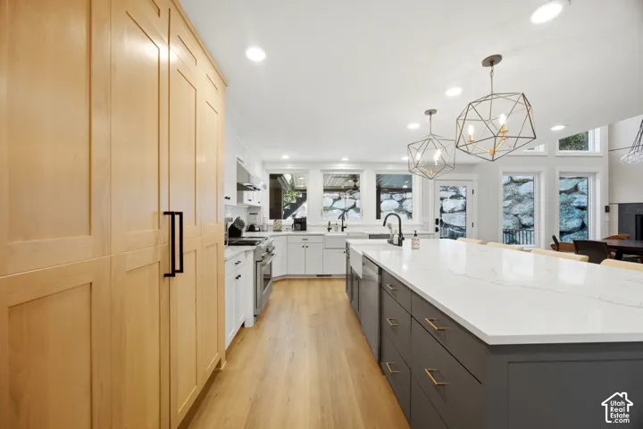Spacious kitchen with a large central island, light wood-finish flooring, recessed lighting, and expansive windows