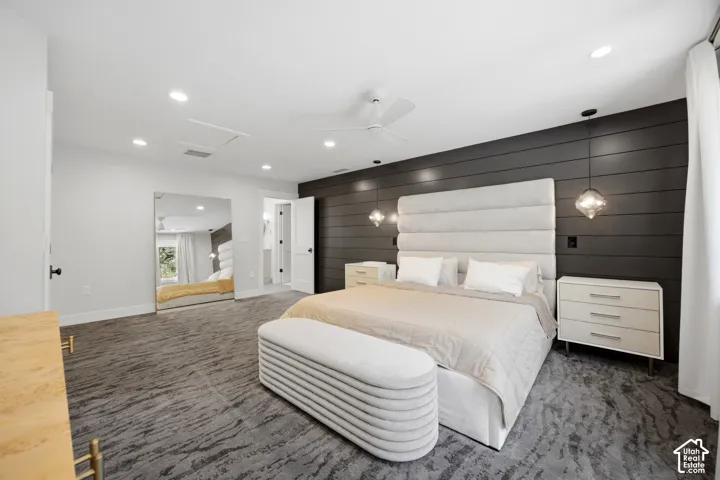 Patterned carpet flooring, recessed lighting, ceiling fan, dark shiplap accent wall, and built-in closet with mirrored doors
