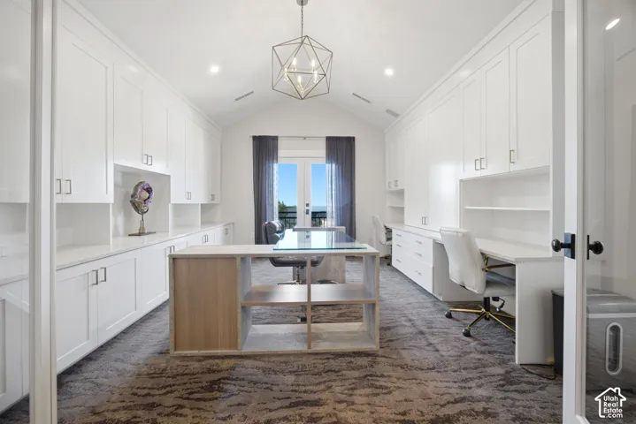 Vaulted ceilings, built-in cabinetry, dual workstations, central island with open shelving, and French doors