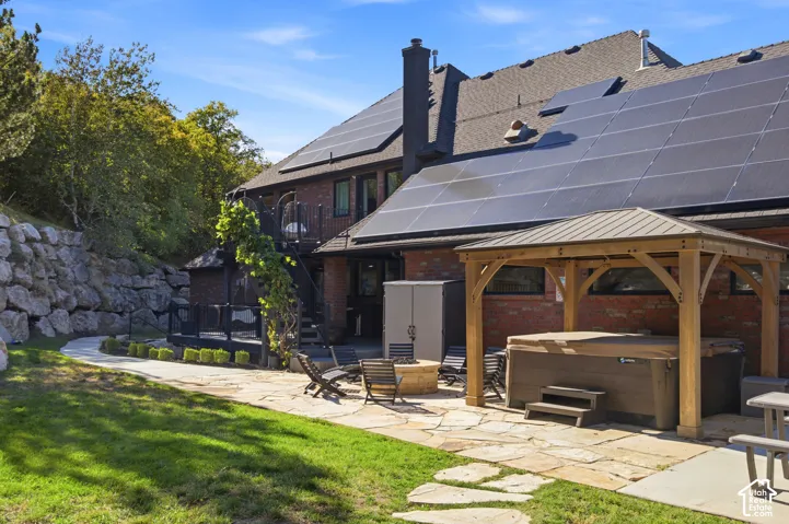 Brick exterior with solar panels, flagstone patio, and a wooden gazebo