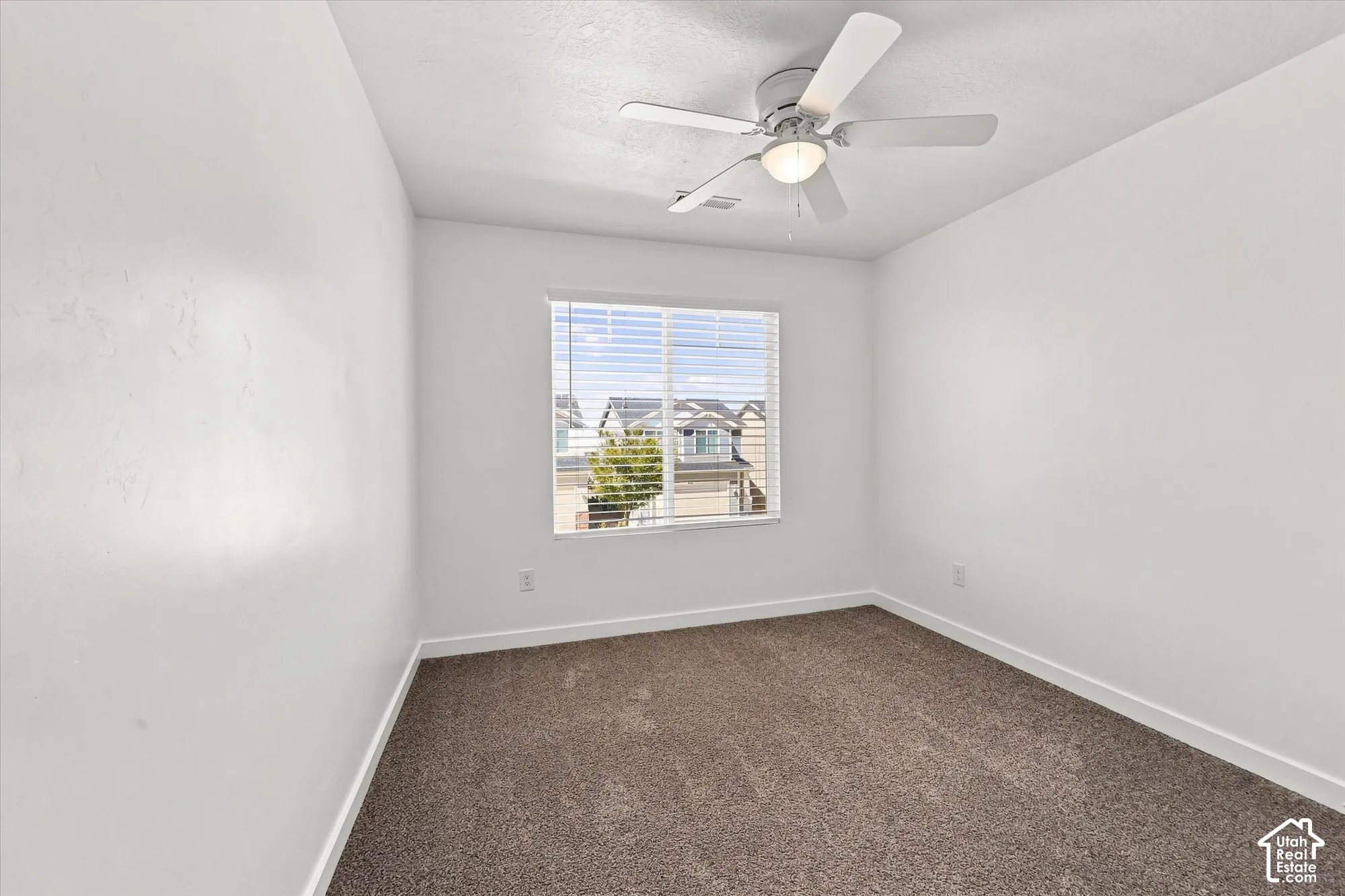 Recessed window with blinds, overhead ceiling fan with light, and neutral-toned carpet