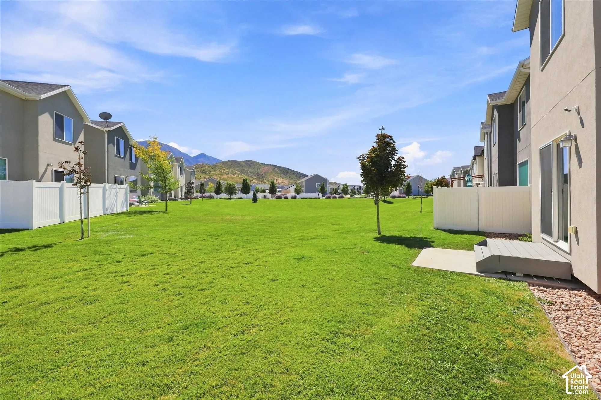 Expansive grassy area with mature trees and a mountain backdrop