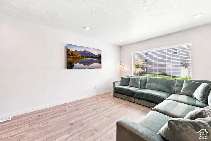 Recessed ceiling lighting, wood-finish flooring, and a large window with horizontal blinds "wall color is altered"