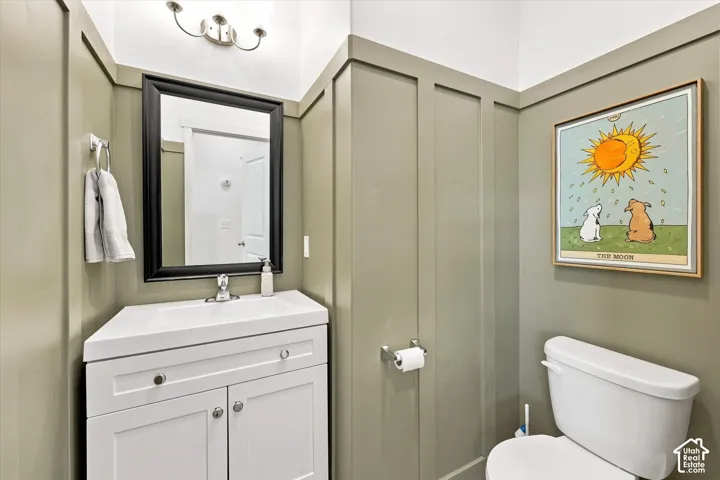 half bath on main floor White vanity with integrated sink, panel molding, and wall-mounted light fixture