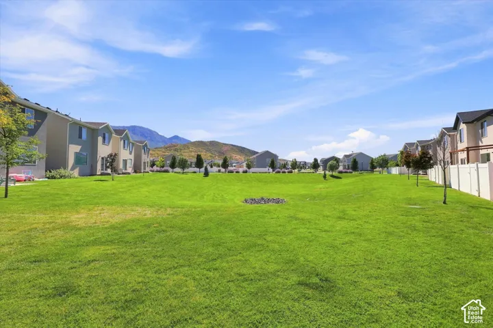 Expansive green space bordered by residential structures and mountain scenery