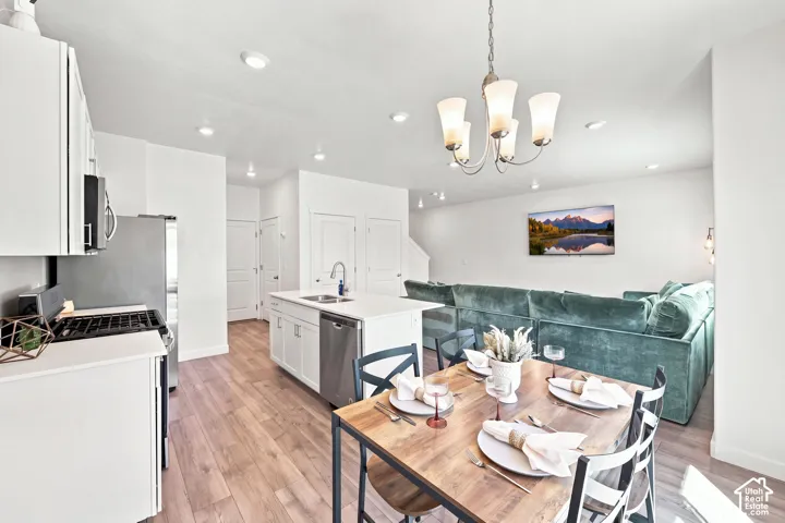 Open-concept living space featuring wood-finish flooring, recessed lighting, and a modern chandelier "wall color is altered"