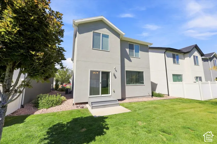 Expansive backyard featuring a manicured lawn, gravel landscaping, and a sliding glass door with an exterior landing