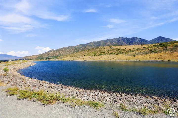 Expansive water frontage with a rocky shore and mountain backdrop under a clear sky