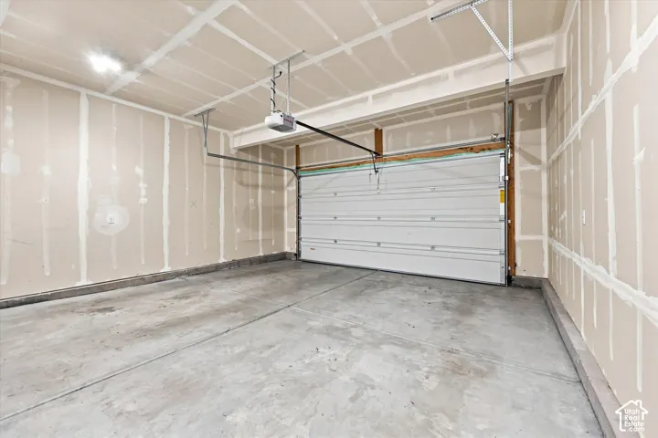 Concrete flooring with a white sectional garage door and exposed wall framing