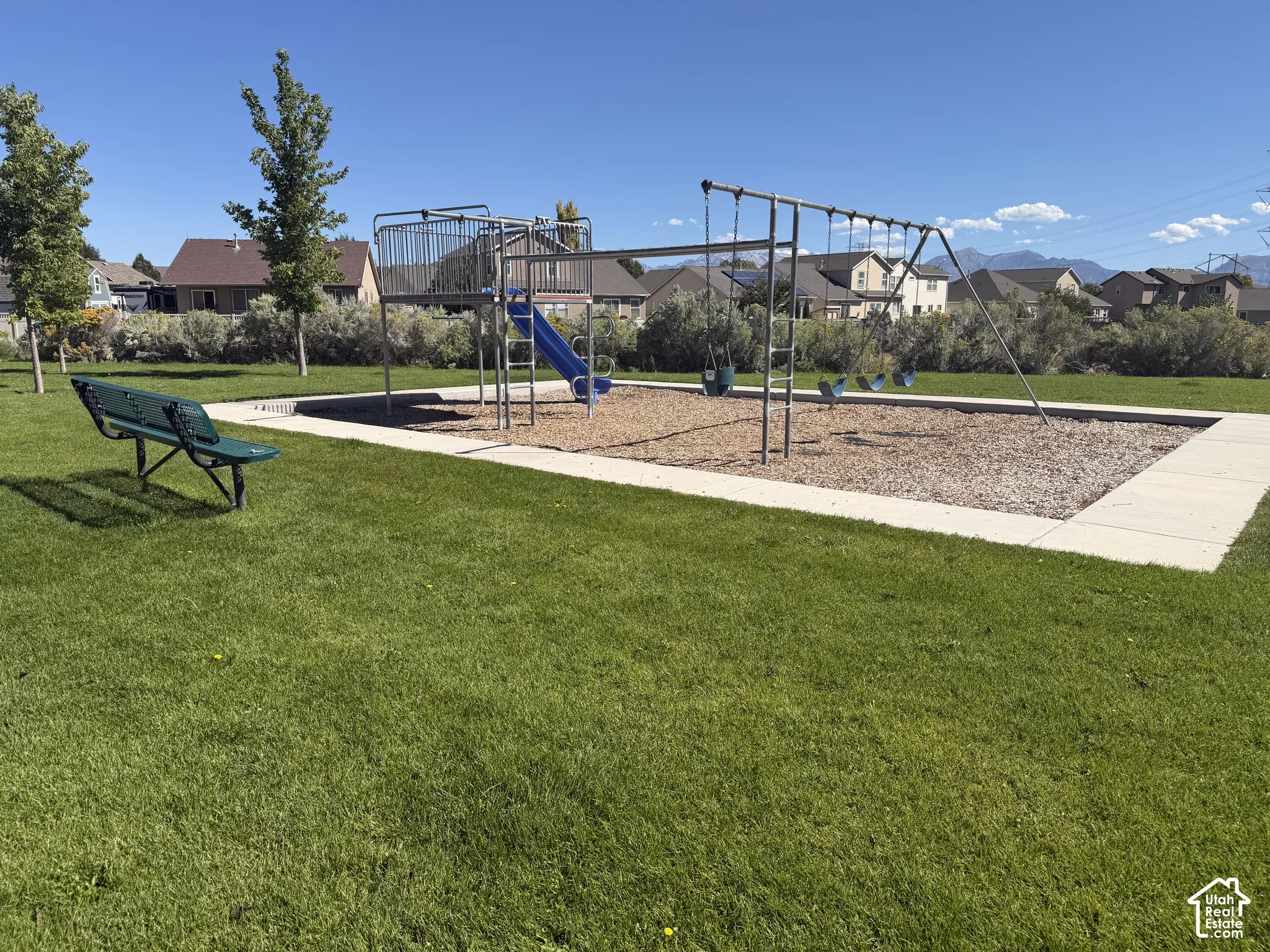 Manicured green lawn with a playground featuring a slide and swing set