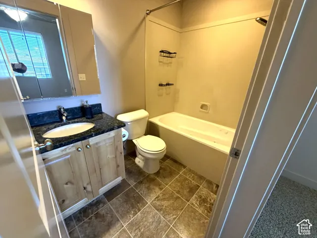 Bathroom featuring a vanity with a dark countertop, an undermount sink, and wood-finish cabinetry