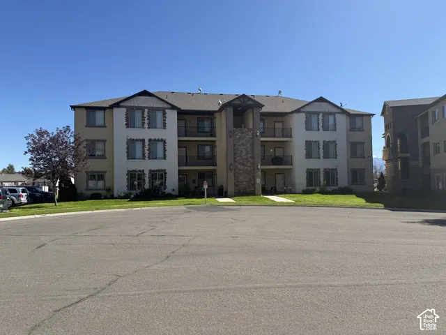 Three-story building with a stucco and stone veneer exterior, featuring multiple balconies with black railings