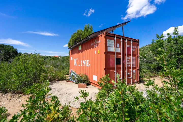 Shipping container structure featuring solar panels and a natural, undeveloped setting