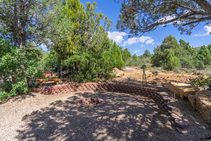 Outdoor gathering area featuring a brick-lined fire pit, natural stone seating, and a gravel surface