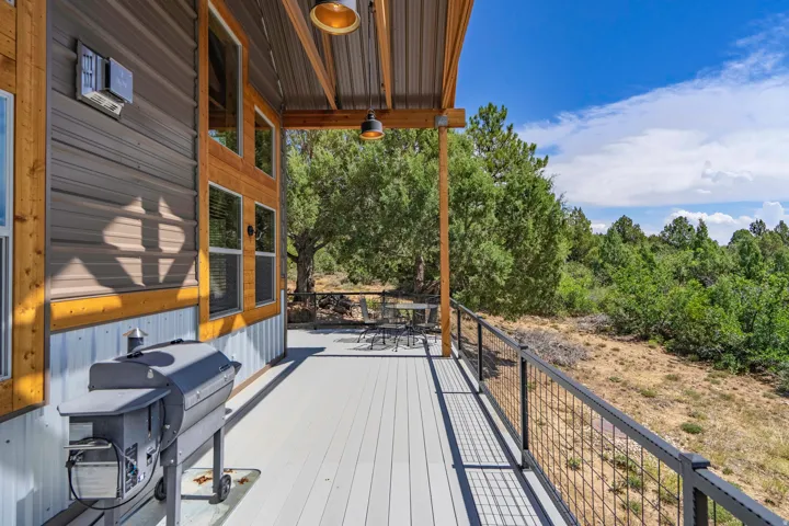 Expansive outdoor deck featuring composite decking, metal railing, and a covered patio area with exposed wood beams and recessed lighting