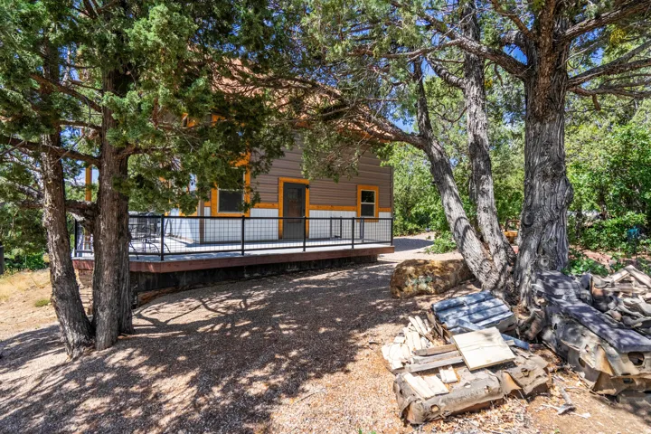 Exterior featuring wood siding, a dark trim deck with a black metal railing, and exposed aggregate gravel surrounding the property