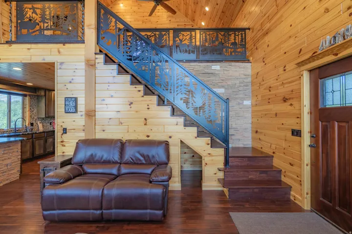 Vaulted wood-paneled ceilings, wood-finish flooring, custom metal railing, and a stone accent wall