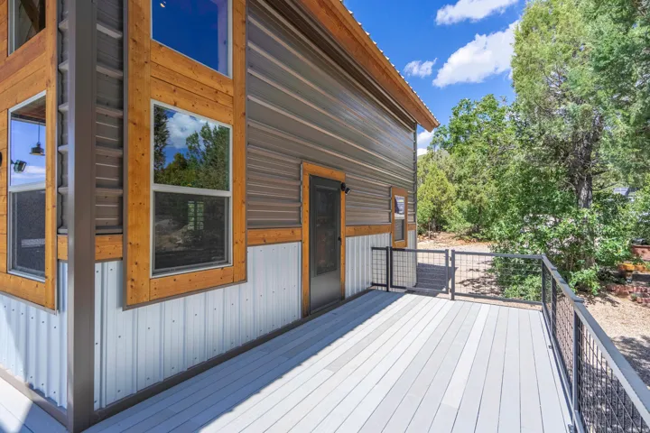 Exterior featuring corrugated metal siding, wood-framed windows, a deck with composite decking, and metal railings