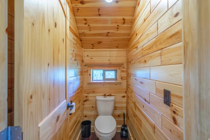 Pine wood-paneled walls and ceiling, natural wood door, and compact window