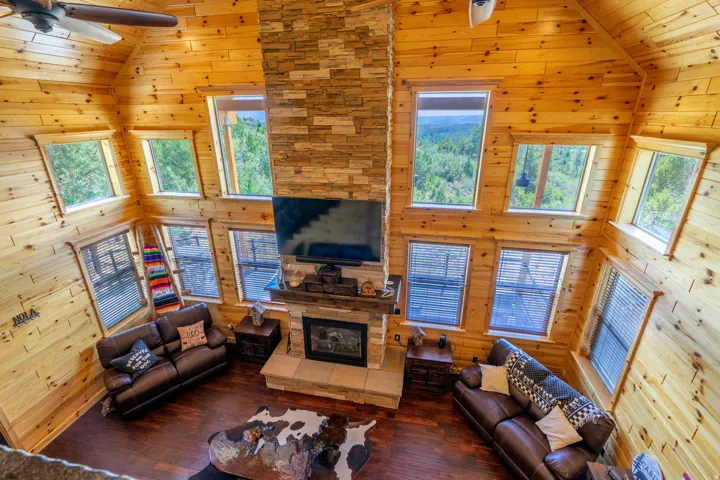 Soaring vaulted ceilings and abundant natural light define this open-concept great room, featuring extensive wood-finish walls and ceiling throughout