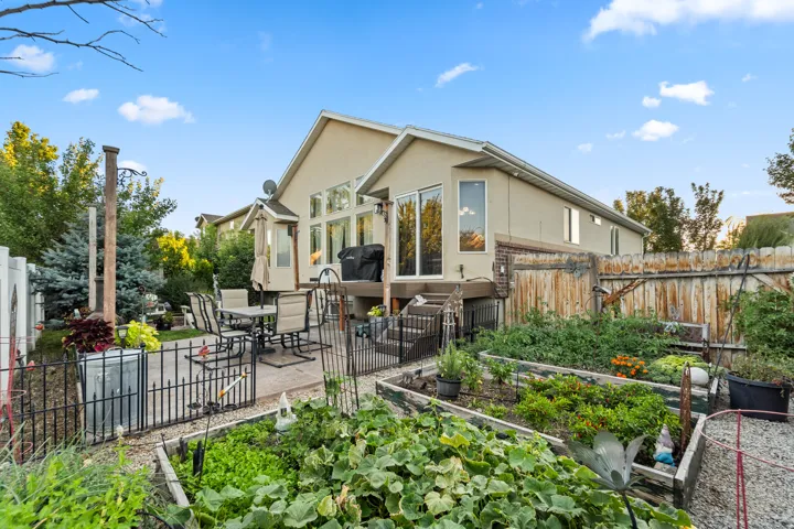 Raised garden beds, stone paver patio, wood privacy fence, multi-level deck, and large windows