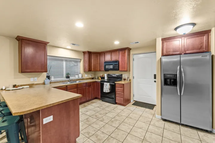 Mother in Law  Kitchen featuring warm wood cabinetry, light-colored countertops, tile flooring, and integrated stainless steel appliances