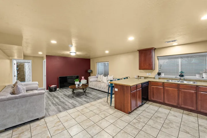 Mother in Law Kitchen featuring wood-finish cabinetry, built-in dishwasher, stainless steel sink, and light-toned countertops
