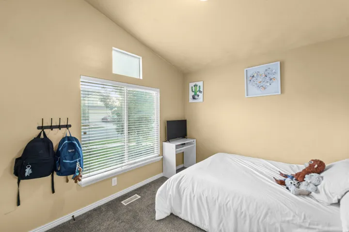 Front Bedroom Vaulted ceiling with an upper transom window, large window with blinds, and durable carpeting