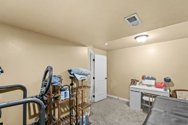 Recessed lighting and ceiling-mounted fixture illuminate the textured walls and grey carpet flooring