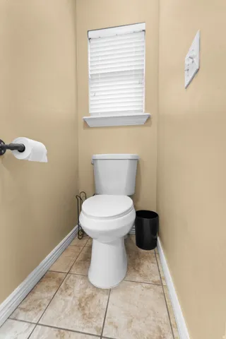Master Bathroom Window with white blinds, ceramic floor tiling, and a white toilet