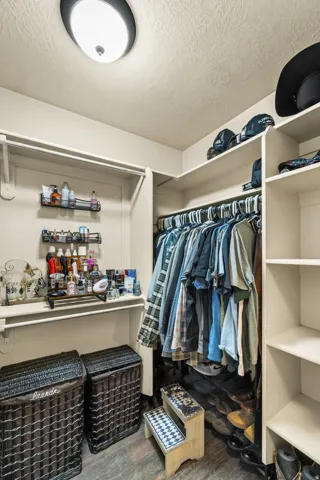 Master Bathroom Walk-in closet featuring built-in shelving, hanging rods, and wood-finish flooring
