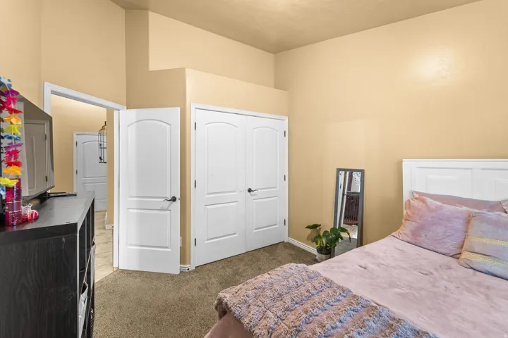 Second Bedroom White paneled doors, carpeted flooring, and a white paneled headboard