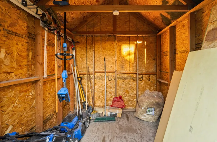 Utility shed with exposed wood framing, oriented strand board walls, and pitched roofline