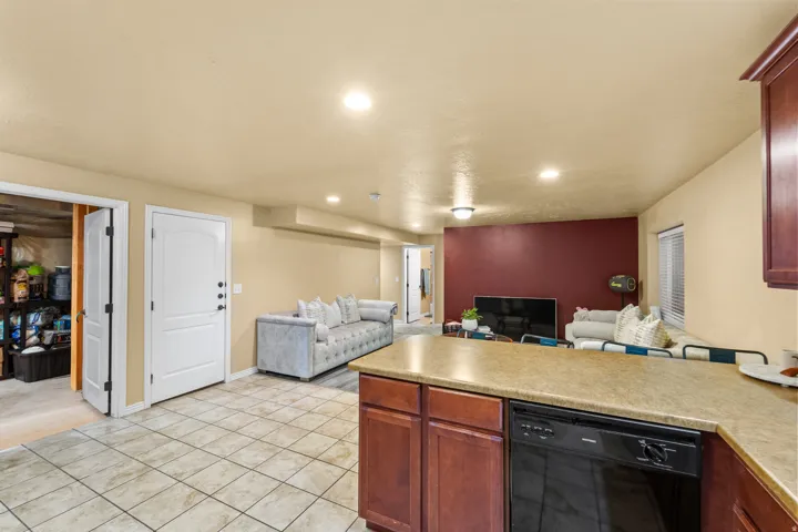 Mother in Law  Kitchen counter with a built-in dishwasher, tile flooring, recessed lighting, and a kitchen island with stone-finish countertops