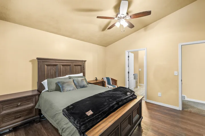 Vaulted ceilings with a ceiling fan, wood-finish flooring, and a paneled door