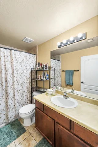 Wood-finish vanity with a light-toned countertop, oval sink, and chrome faucet